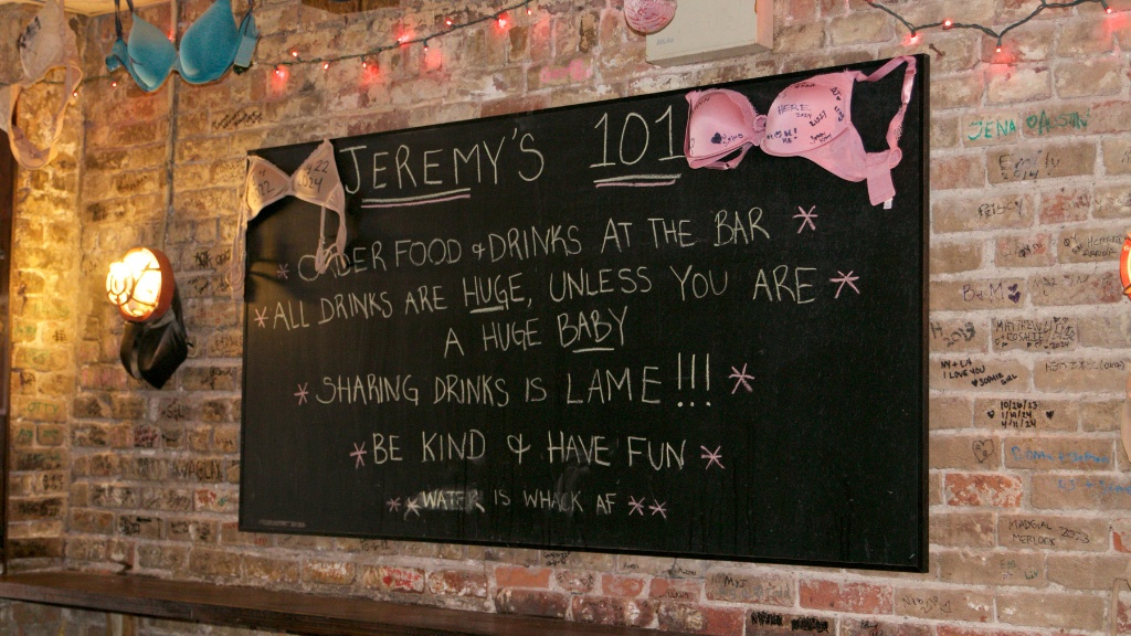 Blackboard at Jeremy's Ale House reading: "Jeremy's 101. Order Food and Drinks at the bar. All Drinks are HUGE, unless you are a huge baby. Sharing drinks is lame!!! Be kind and have fun. Water is whack AF."