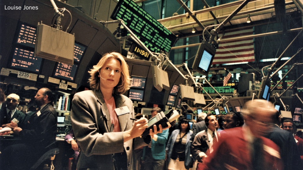 Blonde woman in gray jacket on floor of New York Stock Exchange.