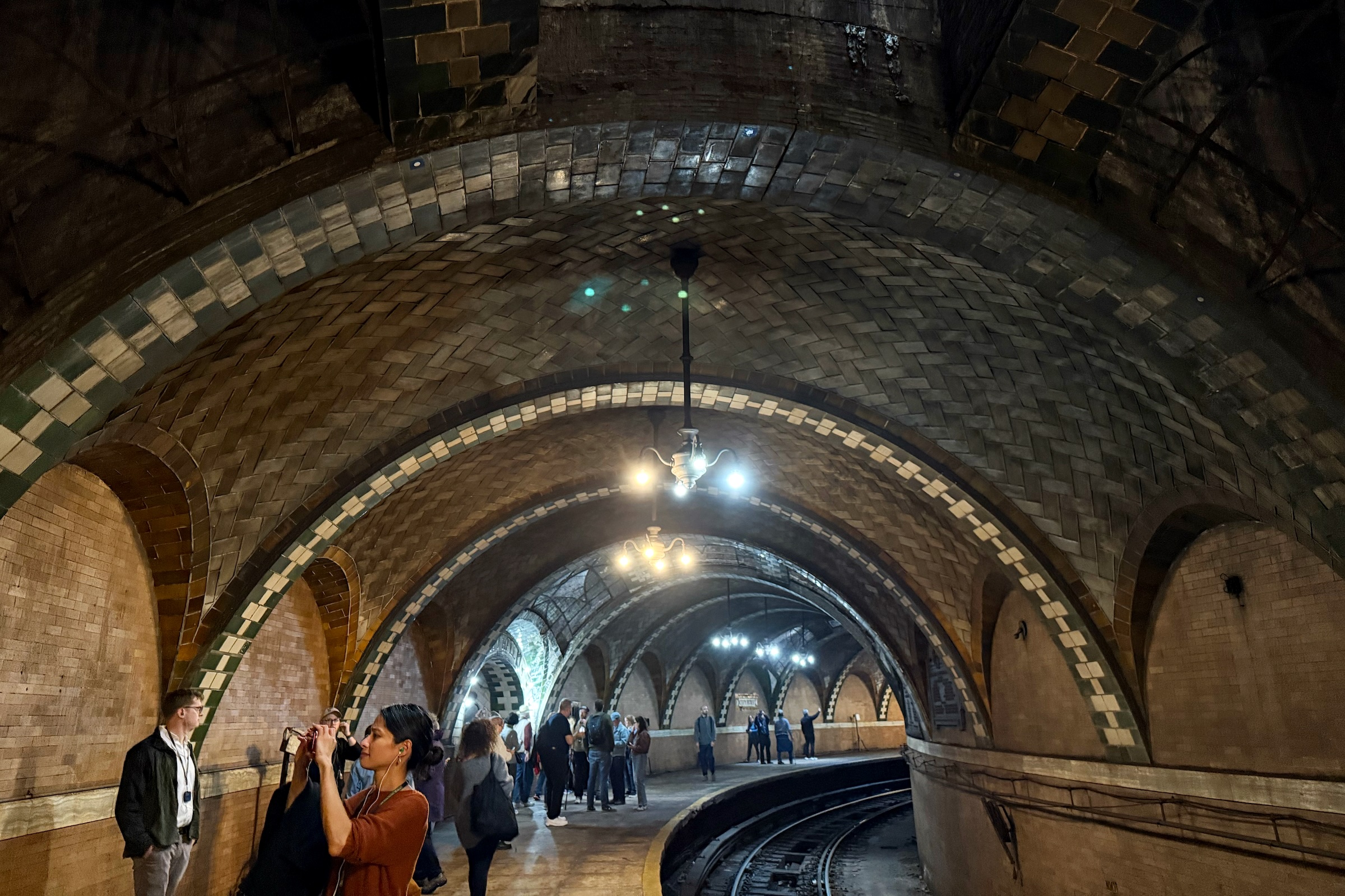 People walking through arched brick subway tunnel.