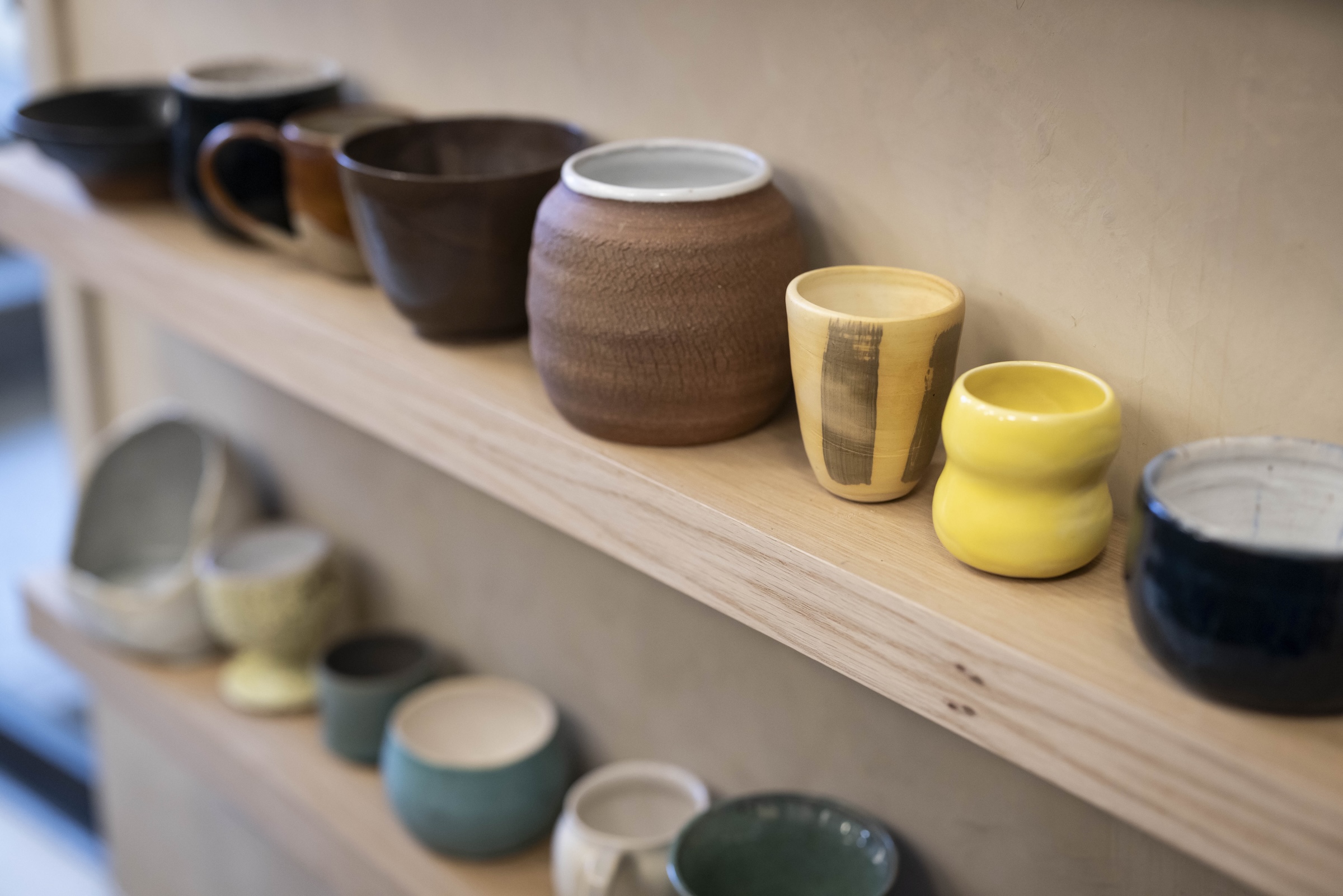A wall of ceramic mugs on wooden shelves.