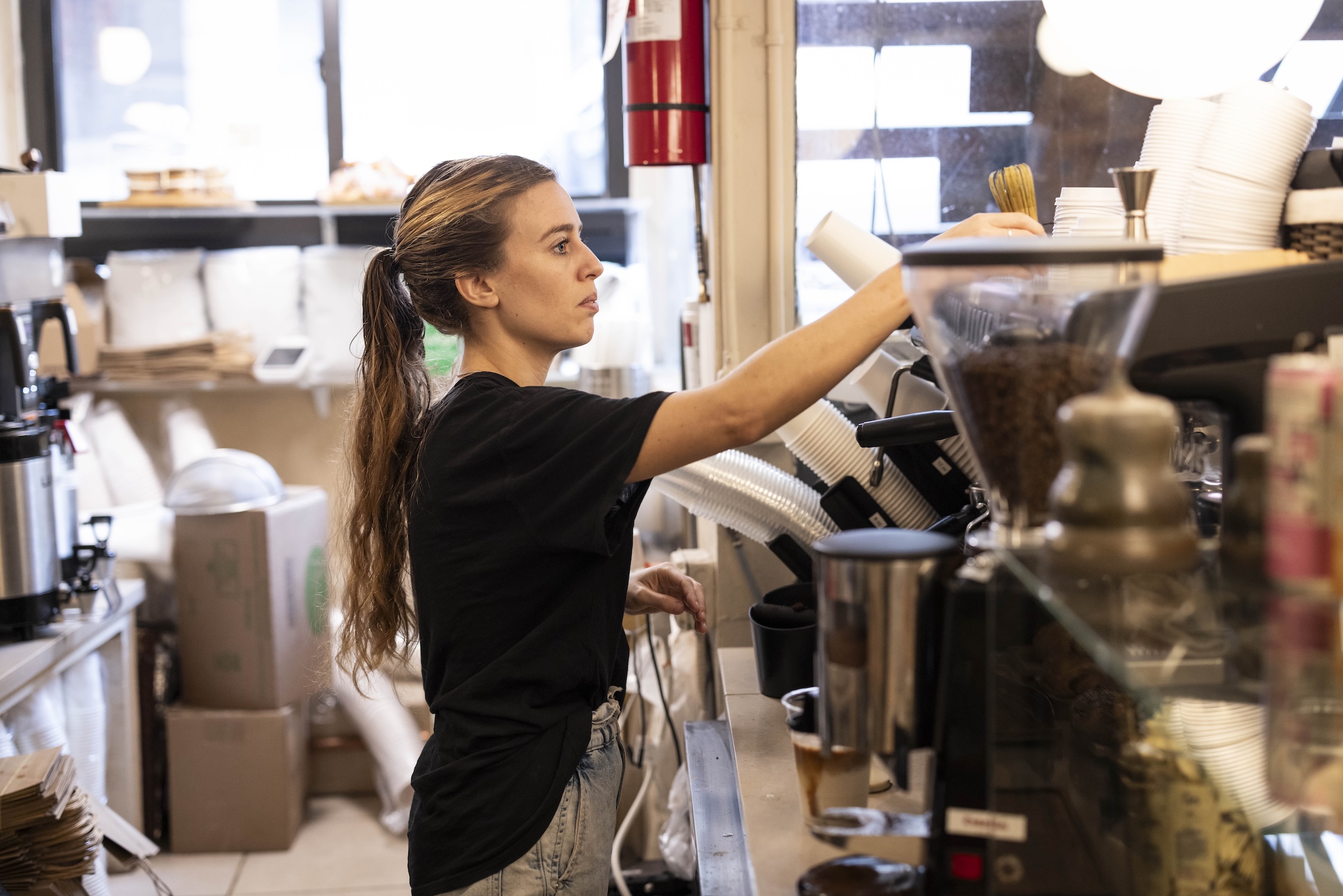 A woman behind the barista counter at a coffee shop.
