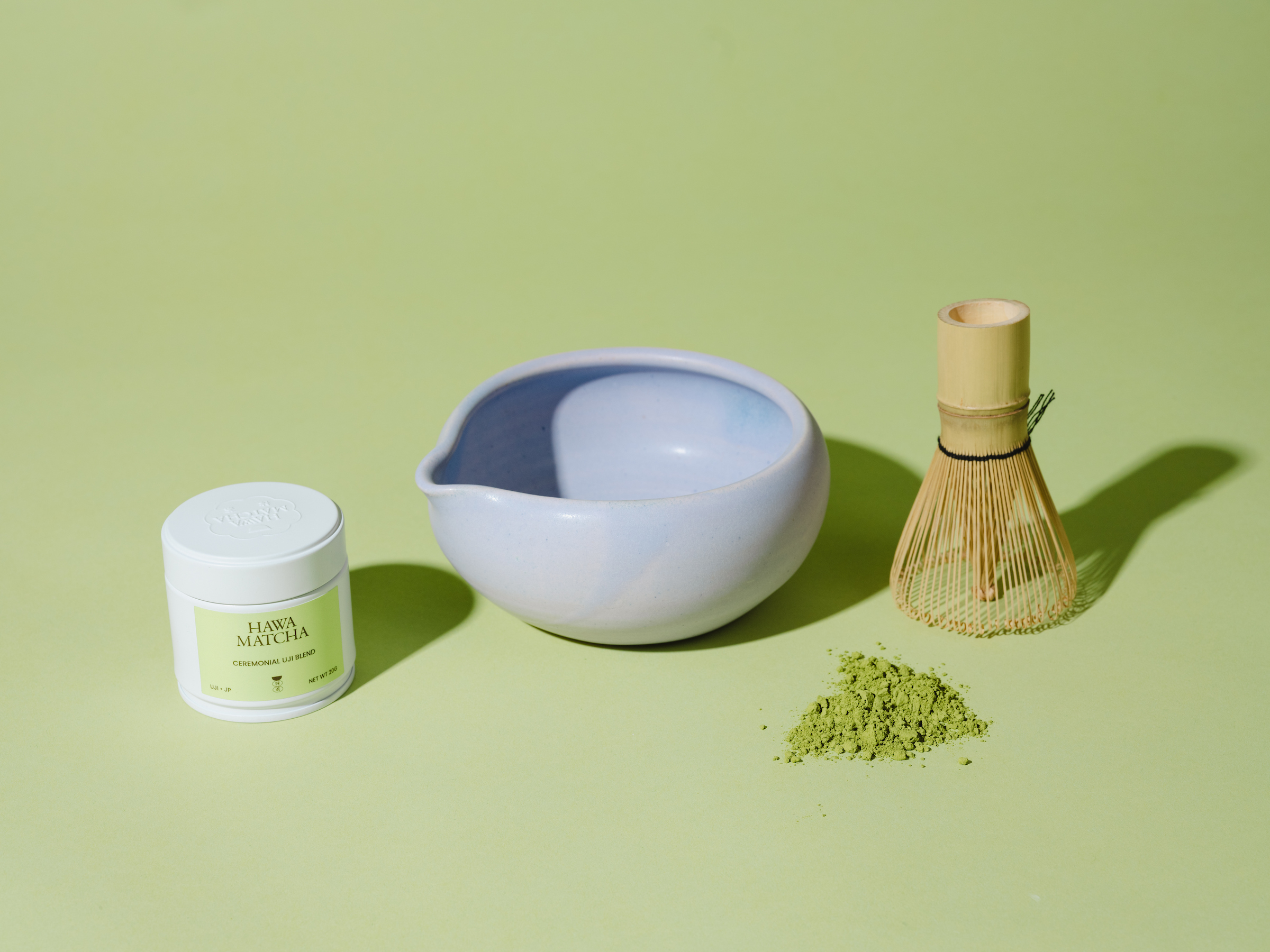 Matcha grains, mixer, bowl and container reading "Hawa Matcha" on mint green background.