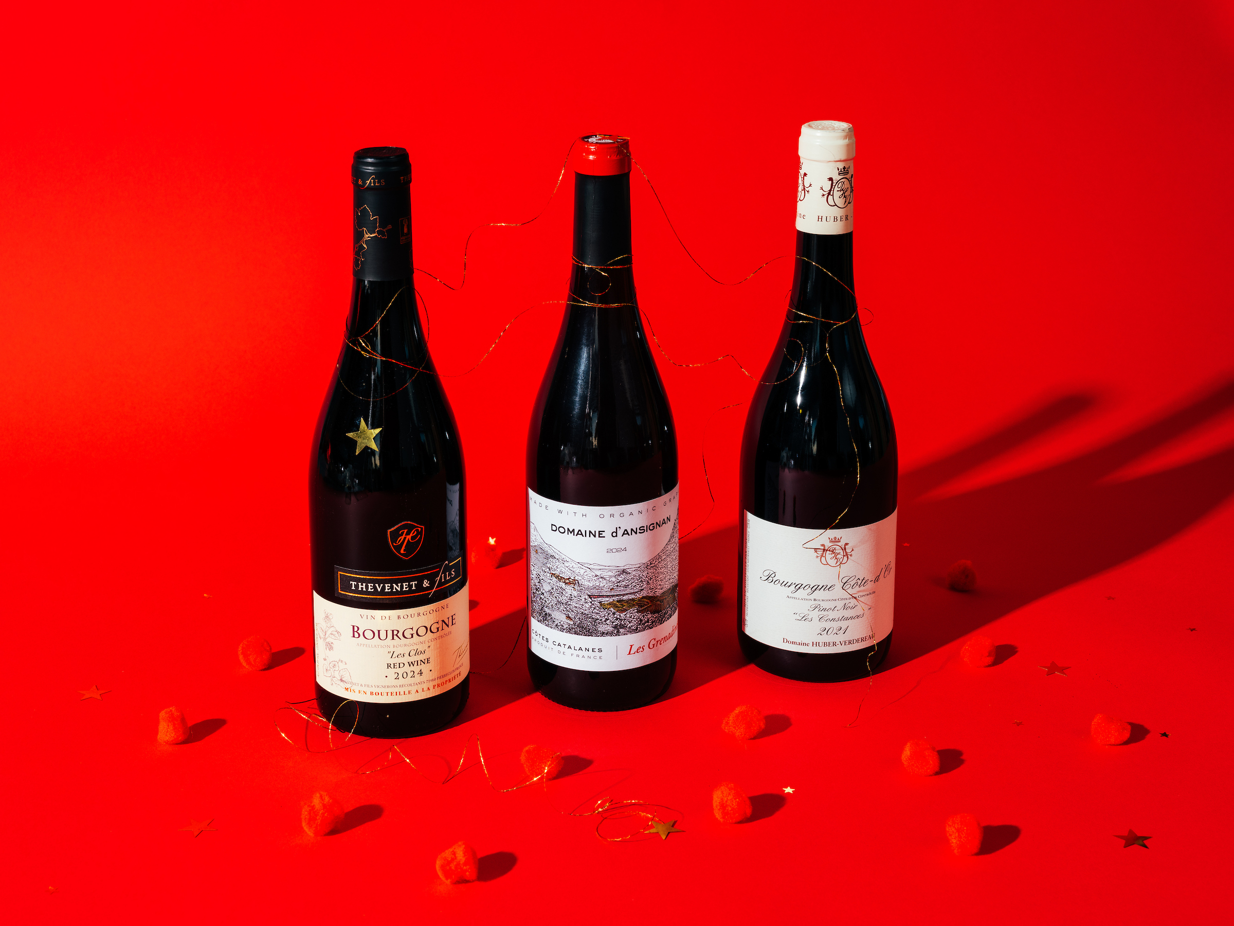 Three bottles of wine against red backdrop with stars.