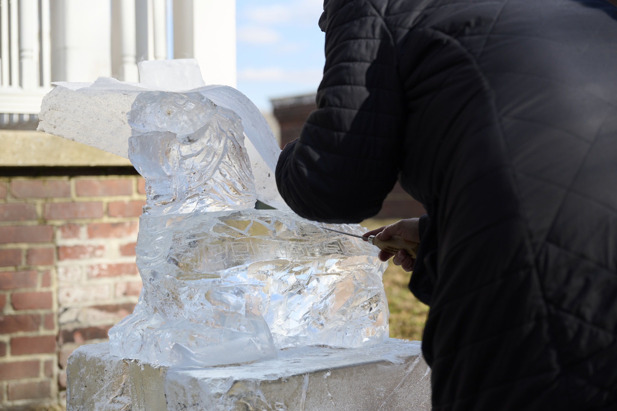Artist works on ice sculpture at Governors Island Winter Ice Sculpture show.