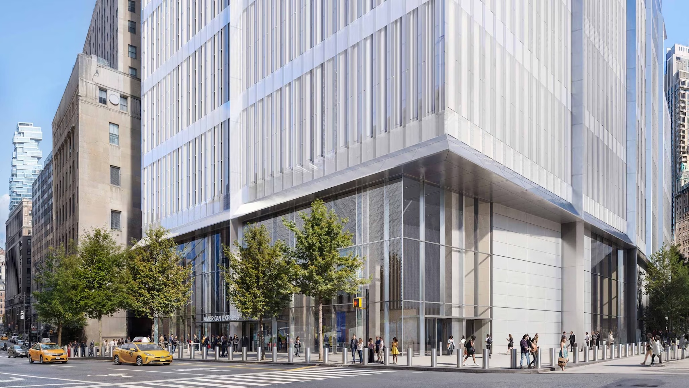 A street-level architectural rendering of a modern, multi-story building at a busy city intersection. The building's ground floor features high glass walls and a prominent entrance with "AMERICAN EXPRESS" signage. The upper facade is composed of light-colored vertical panels. Pedestrians walk along the sidewalk, and yellow taxis are visible on the street in front of the building. In the background, other city skyscrapers, including a distinctively tiered tower, are visible under a clear, bright sky.